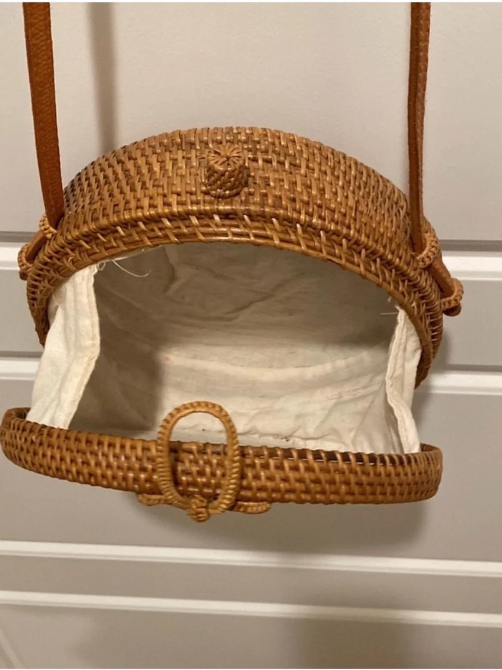 Tan, round, handwoven rattan crossbody bag